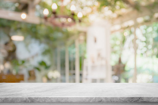 Fototapeta Empty white marble stone table top and blurred of interior room with window view from green tree garden background background - can used for display or montage your products.