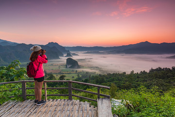 Fototapeta na wymiar Young gril in red jacket hiking on Phu- lang-ka, Payao province, Thailand.