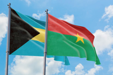 Burkina Faso and Bahamas flags waving in the wind against white cloudy blue sky together. Diplomacy concept, international relations.