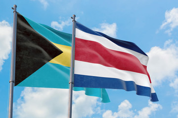 Fototapeta na wymiar Costa Rica and Bahamas flags waving in the wind against white cloudy blue sky together. Diplomacy concept, international relations.