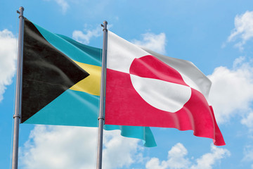 Greenland and Bahamas flags waving in the wind against white cloudy blue sky together. Diplomacy concept, international relations.