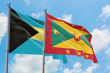 Grenada and Bahamas flags waving in the wind against white cloudy blue sky together. Diplomacy concept, international relations.