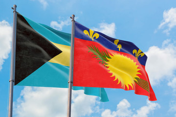 Guadeloupe and Bahamas flags waving in the wind against white cloudy blue sky together. Diplomacy concept, international relations.