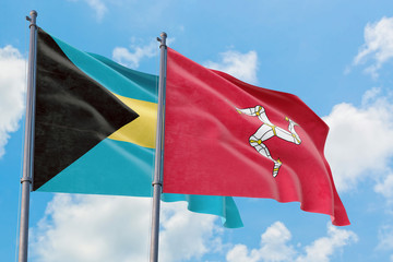 Isle Of Man and Bahamas flags waving in the wind against white cloudy blue sky together. Diplomacy concept, international relations.