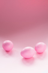 Fototapeta na wymiar Three pink eggs lie randomly on a pink ombre background. Monochrome