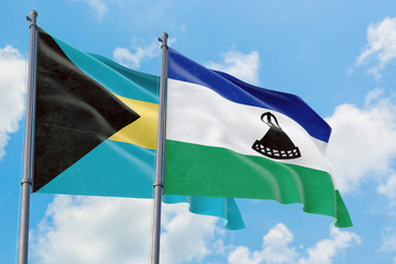 Lesotho and Bahamas flags waving in the wind against white cloudy blue sky together. Diplomacy concept, international relations.