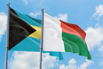Madagascar and Bahamas flags waving in the wind against white cloudy blue sky together. Diplomacy concept, international relations.