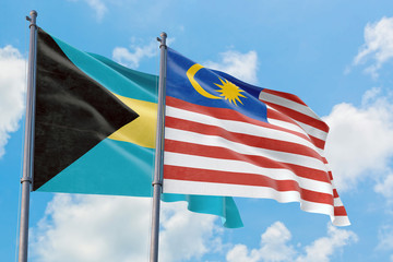 Malaysia and Bahamas flags waving in the wind against white cloudy blue sky together. Diplomacy concept, international relations.