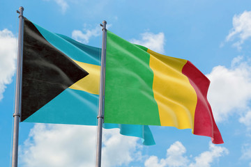 Mali and Bahamas flags waving in the wind against white cloudy blue sky together. Diplomacy concept, international relations.