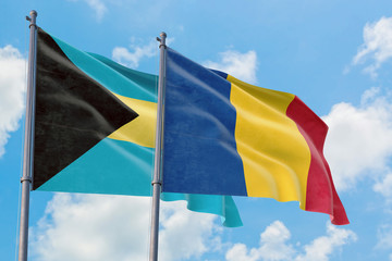 Romania and Bahamas flags waving in the wind against white cloudy blue sky together. Diplomacy concept, international relations.