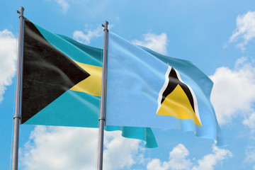 Saint Lucia and Bahamas flags waving in the wind against white cloudy blue sky together. Diplomacy concept, international relations.