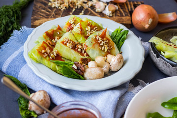 Cabbage rolls with mushrooms and tomato paste sauce walnuts topping. Healthy dietary vegan food. Woman holds cabbage rolls