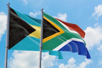 South Africa and Bahamas flags waving in the wind against white cloudy blue sky together. Diplomacy concept, international relations.