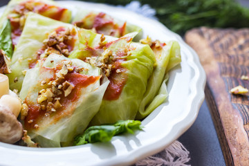 Cabbage rolls with mushrooms and tomato paste sauce walnuts topping. Healthy dietary vegan food. Woman holds cabbage rolls