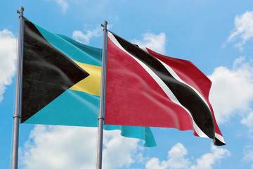 Trinidad And Tobago and Bahamas flags waving in the wind against white cloudy blue sky together. Diplomacy concept, international relations.