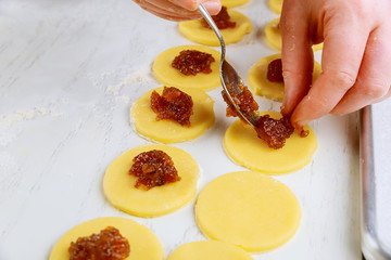 Filling raw cookie dough circles with jam.