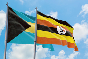 Uganda and Bahamas flags waving in the wind against white cloudy blue sky together. Diplomacy concept, international relations.