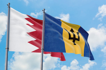 Barbados and Bahrain flags waving in the wind against white cloudy blue sky together. Diplomacy concept, international relations.