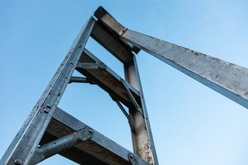 Gardening tool and equipment. A single aluminum garden ladder standing under the clear sky. Close-up and low angle view
