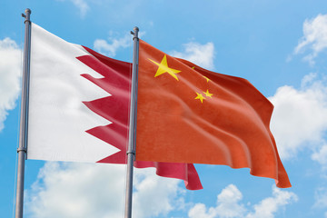 China and Bahrain flags waving in the wind against white cloudy blue sky together. Diplomacy concept, international relations.