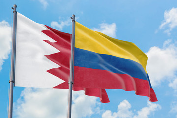 Fototapeta na wymiar Colombia and Bahrain flags waving in the wind against white cloudy blue sky together. Diplomacy concept, international relations.