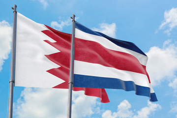 Costa Rica and Bahrain flags waving in the wind against white cloudy blue sky together. Diplomacy concept, international relations.