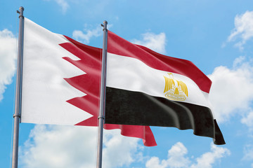 Egypt and Bahrain flags waving in the wind against white cloudy blue sky together. Diplomacy concept, international relations.