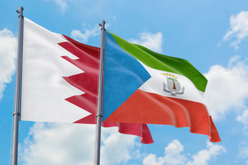 Equatorial Guinea and Bahrain flags waving in the wind against white cloudy blue sky together. Diplomacy concept, international relations.
