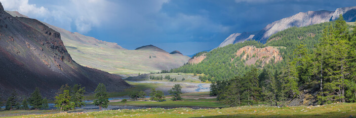 Panoramic view. Mountain valley, contrast of light and stormy sky.