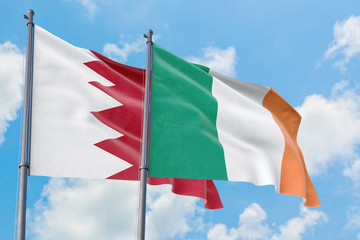 Ireland and Bahrain flags waving in the wind against white cloudy blue sky together. Diplomacy concept, international relations.