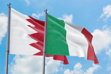 Italy and Bahrain flags waving in the wind against white cloudy blue sky together. Diplomacy concept, international relations.
