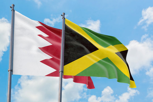 Jamaica and Bahrain flags waving in the wind against white cloudy blue sky together. Diplomacy concept, international relations.