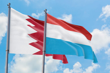Fototapeta na wymiar Luxembourg and Bahrain flags waving in the wind against white cloudy blue sky together. Diplomacy concept, international relations.