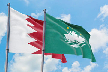 Macao and Bahrain flags waving in the wind against white cloudy blue sky together. Diplomacy concept, international relations.