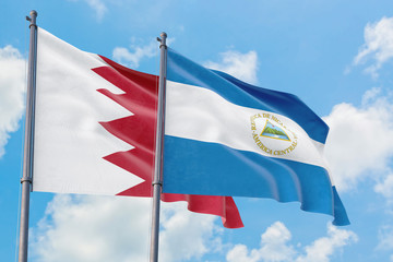 Nicaragua and Bahrain flags waving in the wind against white cloudy blue sky together. Diplomacy concept, international relations.
