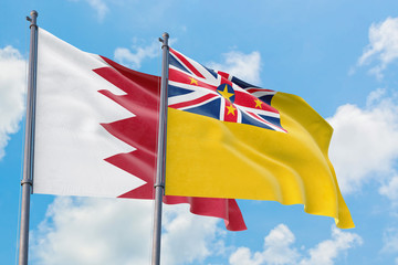 Niue and Bahrain flags waving in the wind against white cloudy blue sky together. Diplomacy concept, international relations.