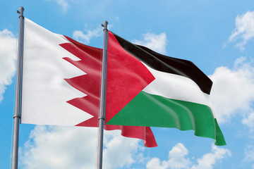 Palestine and Bahrain flags waving in the wind against white cloudy blue sky together. Diplomacy concept, international relations.