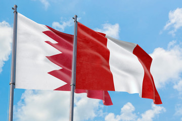 Peru and Bahrain flags waving in the wind against white cloudy blue sky together. Diplomacy concept, international relations.