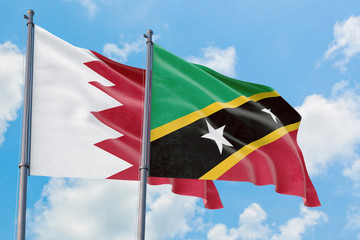 Saint Kitts And Nevis and Bahrain flags waving in the wind against white cloudy blue sky together. Diplomacy concept, international relations.