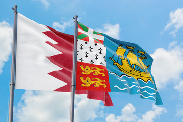 Saint Pierre And Miquelon and Bahrain flags waving in the wind against white cloudy blue sky together. Diplomacy concept, international relations.