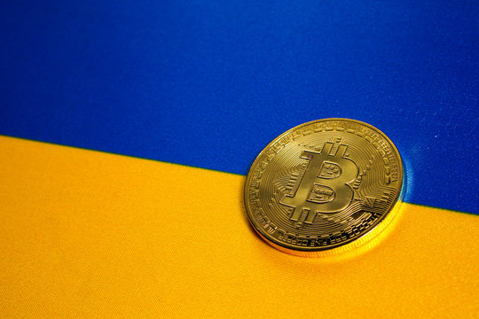 Golden Bitcoin on the flag of Ukraine. Close-up, copy space