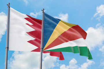 Seychelles and Bahrain flags waving in the wind against white cloudy blue sky together. Diplomacy concept, international relations.