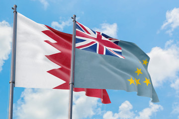 Tuvalu and Bahrain flags waving in the wind against white cloudy blue sky together. Diplomacy concept, international relations.