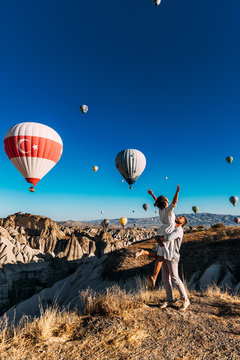 Honeymoon trip. Couple in love among balloons. A man proposes to a girl. Couple in love in Cappadocia. Couple in Turkey.  Man and woman traveling. Festival of balloons. The couple travels the world