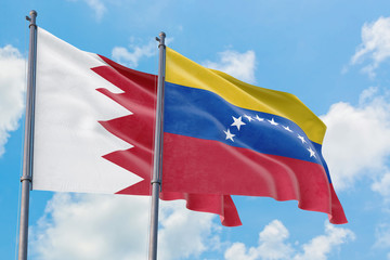 Venezuela and Bahrain flags waving in the wind against white cloudy blue sky together. Diplomacy...