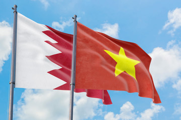 Vietnam and Bahrain flags waving in the wind against white cloudy blue sky together. Diplomacy concept, international relations.