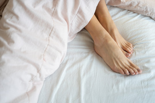 Woman with bare feet relaxing in bed