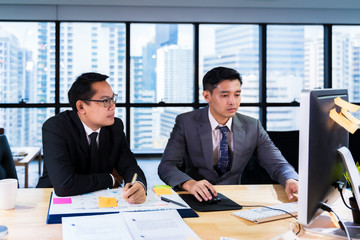 Group of young business people working and communicating while sitting at the office desk together.