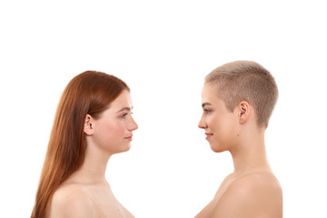 We're all different. Two attractive blonde and red hair women with clean and fresh skin standing opposite each other while posing naked against white background. Natural beauty