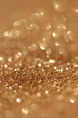 Golden shine background. Gold glitter with golden shiny bokeh. Glitter macro shimmer  texture.Vibrant background with twinkle lights. 